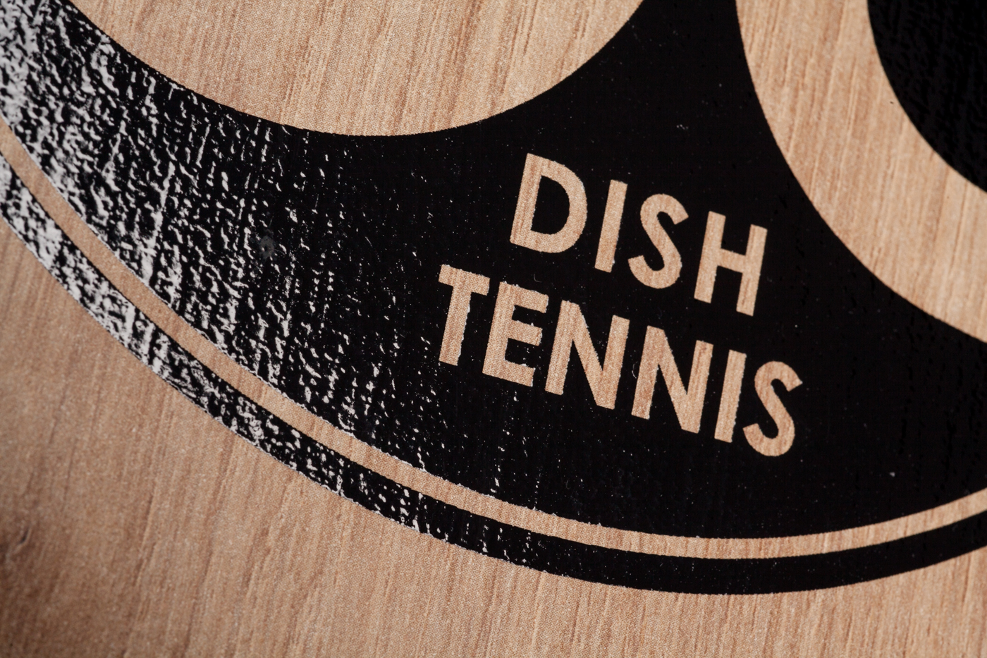 Nahaufnahme der Oberflächenstruktur mit schwarzem, glänzendem Logo der Natur Holz Mini Tischtennisplatte "Der kleine Braune" mit Maserung