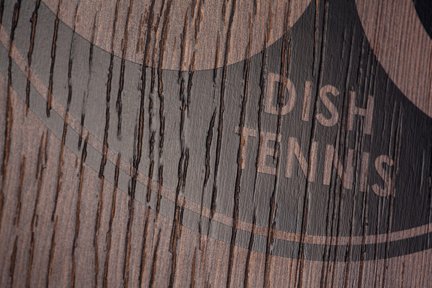 Nahaufnahme der Oberflächenstruktur der Natur Holz Mini Tischtennisplatte "Die Starke Eiche" mit Maserung und schwarzem Logo